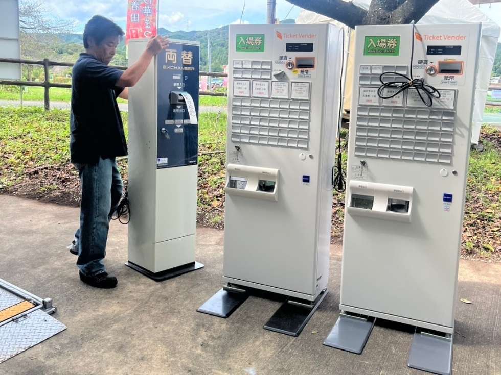 大型の券売機GLORY製VT-B20を株式会社アトラスの代表者が現地で券売機をセッティングしてる写真