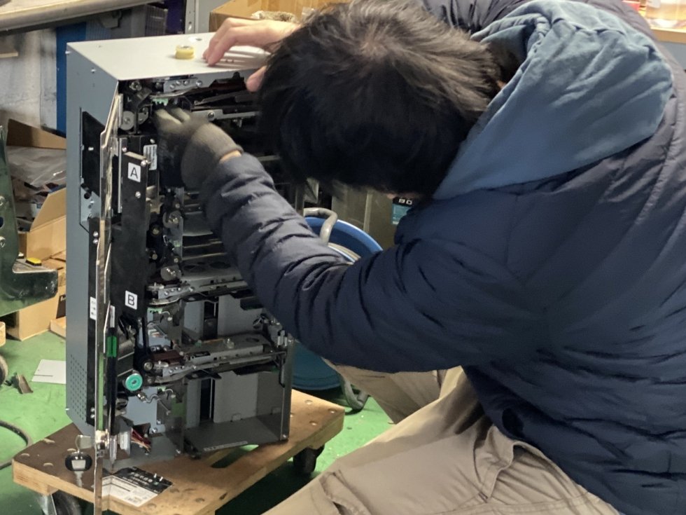 当社スタッフ永田が両替機の払い出しユニットを修理している様子